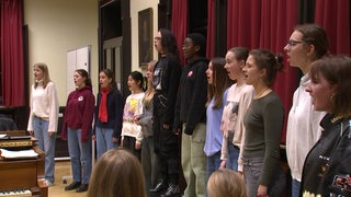 Mehrere Mädchen stehen nebeneinander und singen im Chor. 