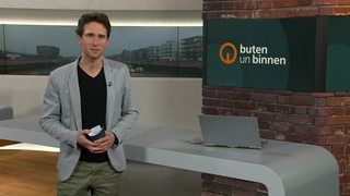 Moderator János Kereszti im Studio von buten un binnen. 