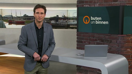 Moderator János Kereszti im Studio von buten un binnen. 