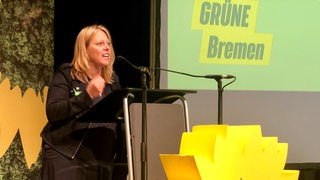 Maike Schaefer steht hinter einem Rednerpult in Bremen