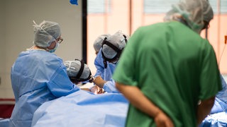 Ein Team aus Ärzten und Operationshelfern steht in einem in der HNO-Operationssaal an einem Tisch.