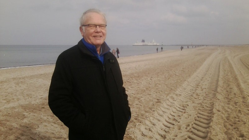 Manfred Grimm steht am Strand