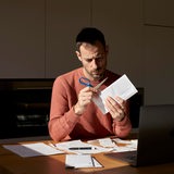 Ein Mann öffnet einen Brief mit einer Schere.