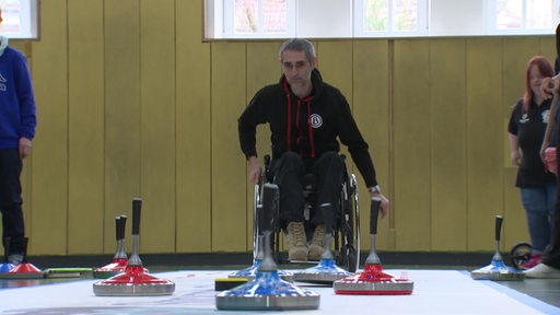 Ein Mann im Rollstuhl spielt eine Partie Stocksport