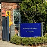 Neben einem Eingangstor steht ein Schild mit der Aufschrift "Admiral Brommy Kaserne".