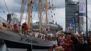 Menschen stehen vor einem Schiff.