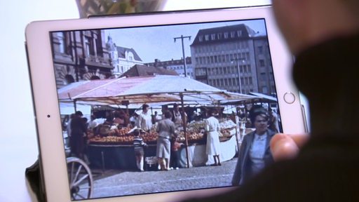 Auf einem Tablet werden alte Archiv-Aufnahmen vom Markt auf dem Bremer Domshof gezeigt.