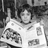 Altes Foto in Schwarzweiß zeigt einen Jungen, der ein Heft mit Abbildungen von Kosmonauten in die Kamera hält.