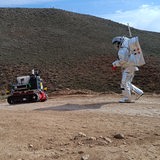 Zwei Astronauten mit Fahrzeug in Wüstenlandschaft