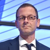 Martin Günthner steht auf einem Podium und schaut in die Kamera.