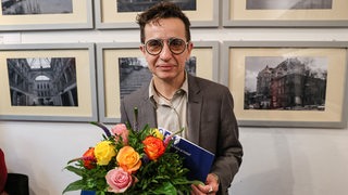 Masha Gessen, Publizistin aus den USA, lächelt nach der Übergabe des Hannah-Arendt-Preises in die Kamera und hält einen Blumenstrauß in der Hand.
