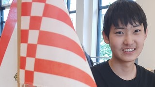 Jizhe Ma, Schüler der 10. Klasse am Lloyd-Gymnasium Bremerhaven neben der Bremer Speckflagge