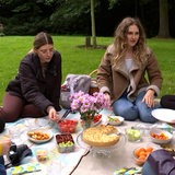 Junge Frauen sitzen für ein Picknick zusammen.