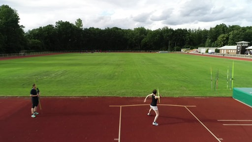 Reporterin Maike Albrecht beim Speerwerfen auf einem Sportplatz