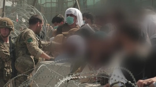 Soldaten und Menschen mit Kindern stehen an den Grenzen in Afghanistan.