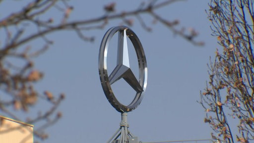Ein großer silberner Mercedes-Stern auf einem Gebäude.