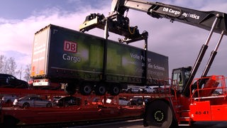Ein Lkw-Anhänger der Deutschen Bahn wird von einem Kran auf einen Schienentransport gehoben
