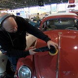Ein Mann poliert einen Oldtimer.
