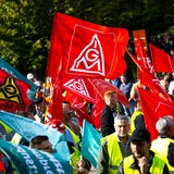 Mit Plakaten und Fahnen stehen die Teilnehmer einer Kundgebung vor der Hauptverwaltung vom Stahlhersteller Arcelormittal.