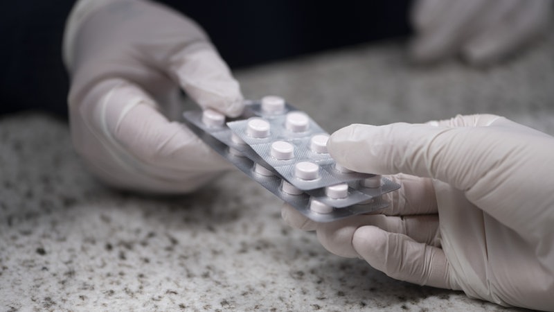 Ein Blister mit Methadon-Tabletten wird über einen Tresen gereicht.
