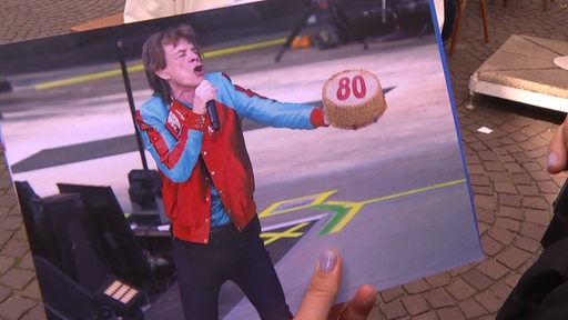 Eine Bildmontage auf der Mick Jagger mit einer Geburtstagstorte zu sehen ist.