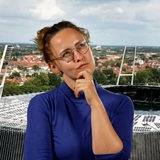 Eine junge Frau, Mirjam Benecke, schaut nachdenklich und steht vor einem Bild des Weser-Stadions