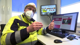 Ein Mitarbeiter von Swb sitzt an seinem Schreibtisch und erklärt anhand seines Bildschirms die neue Technologie in der Abfallwirtschaft.