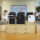 Mehrere Smartphones stehen in einer Holzbox in einem Klassenraum.