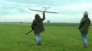 Autor Freddy Radeke mit einem Modelflugzeug in der Hand auf einer großen, grünen Wiese.