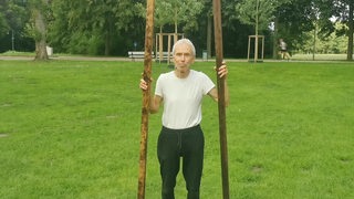 Der "Möglichmacher" Roman Antonic steht mit zwei großen Holzstücken in der Hand in einem Park.