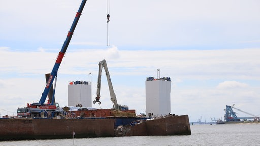 Die abgebrochene Bremerhavener Nordmole im Vordergrund. Der Molenturm ist abgebaut. Im Hintergrund sind Kräne zu sehen. 