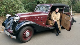 Monica Borgward sitzt in einem alten Auto. 