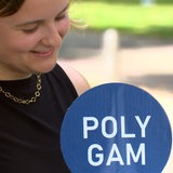Eine junge Frau hält ein Schild mit der Aufschrift "polygam" hoch.