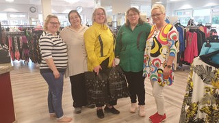 Mehrere Frauen stehen nebeneinander in einem Modegeschäft.
