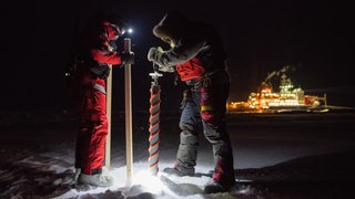 Zwei Wissenschaftler bohren Löcher ins Eis.