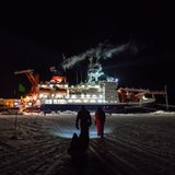 Zwei Personen laufen über das Eis auf das Schiff "Polarstern" zu.