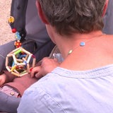 Eine Frau schaut in einen Kinderwagen, in dem ein kleines Kind liegt.