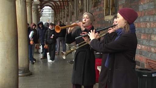 Drei junge Frauen spielen alte Musik auf historischen Instrumenten in der Bremer Innenstadt.