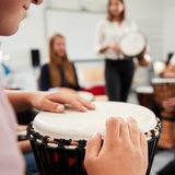 Im Musikunterricht sitzen die Schüler im Kreis und trommeln auf verchiedenen Instrumenten.