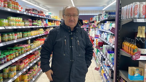 Ein Mann steht im Gang eines Supermarktes.