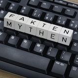 Tastatur, auf der Buchstabenwürfel liegen mit der Aufschrift: "Mythen-Fakten"