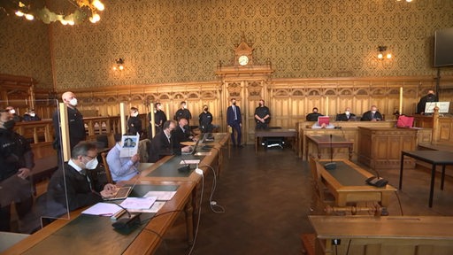 Fünf Männer aus Bremerhaven sitzen vor dem Richter im Bremer Landgericht. 