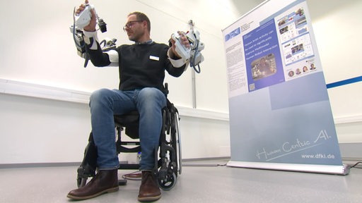 Ein Mann im Rollstuhl mit Exo Skelette im deutschen Forschungs Zentrum für Künstliche Intelligenz. 