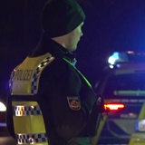 Polizisten stehen vor einem Polizeiauto. 