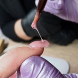 Mit einem Pinsel wird Farbe auf einen Nagel aufgetragen