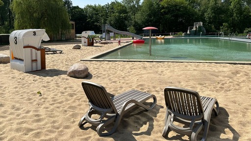 Strand mit Liegen und Strandkörben mit Blick auf das Becken im Naturbad Bassum.