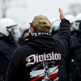 Ein Demonstrant auf einer Hooligan-Veranstaltung skandiert etwas vor einer Gruppe Polizisten.