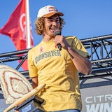 Der Surfer Lennart Neubauer hält eine Trophäe und ein Mikro in der Hand.