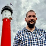 Ein Mann steht vor einem Leuchtturm