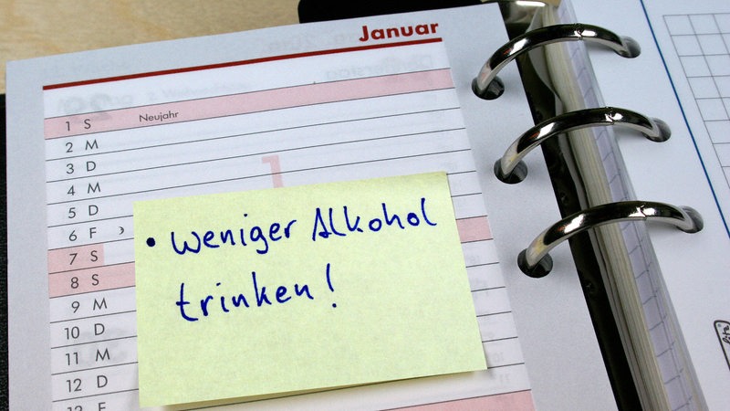 In einem Notizkalender klebt ein Zettel mit der Aufschrift "Weniger Alkohol trinken!"